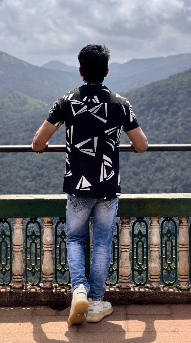 Amar Karthik standing behind a scenic view in a casual black shirt.