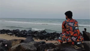 Amar Karthik sitting in front for a beach in a cool evening